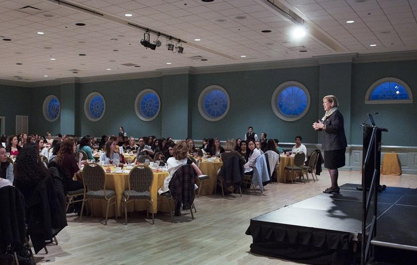 Speaker addressing to people sitting around table in big ballroom