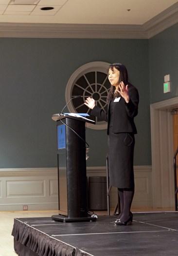 woman speaking on stage hands extend