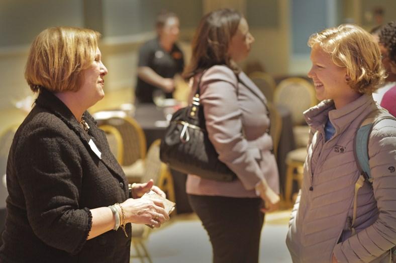 two women chatting another in background