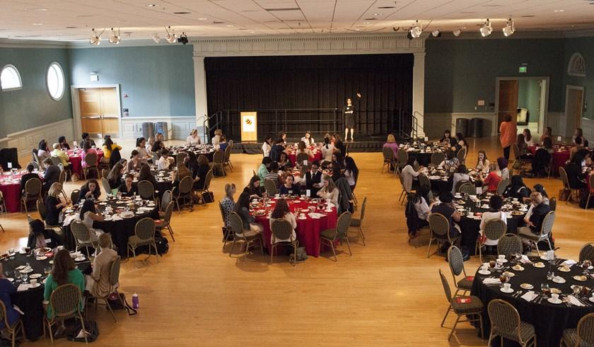 women sitting by tables in a large ball room